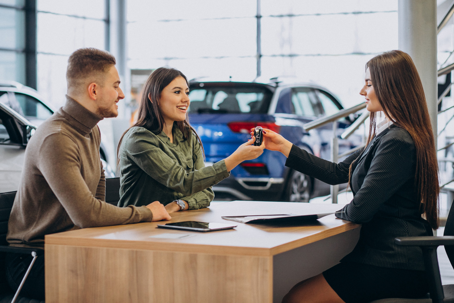 Young couple talking to a sales person in a car showroom Car loan